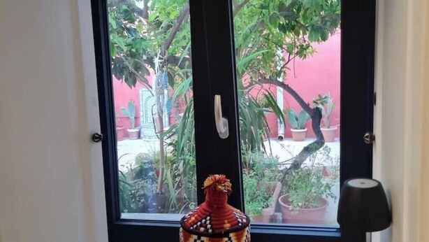 Ein Zimmer mit großem Fenster, einer Zierdevasse und einer Tür mit Griff.
