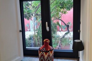 Ein Zimmer mit großem Fenster, einer Zierdevasse und einer Tür mit Griff.