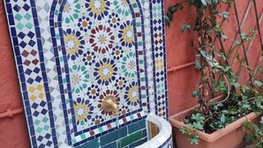 Eine Wand mit Fliesen in einem geometrischen Muster und einem kleinen Brunnen.