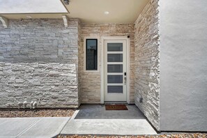 A stone exterior wall, a white door with glass panels, and a 'HELLO' mat. - Modern 3-Story Home, Terrace & Office, Galleria & NRG (Houston)