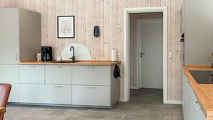 Eine moderne Küche mit einer Holzverkleidung, einer Kaffeemaschine, einem Spülbecken und einem Bilderrahmen.