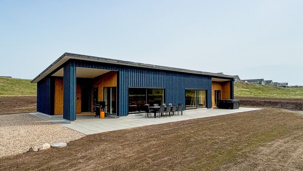 Ein modernes Gebäude mit Flachdach, großen Fenstern und einer offenen Patio mit Außenmöbeln.