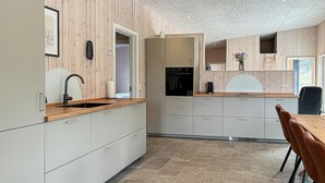 Eine moderne Küche mit Holzausstattung, einem eingebauten Ofen und einem Essbereich mit Tisch und Stühlen.