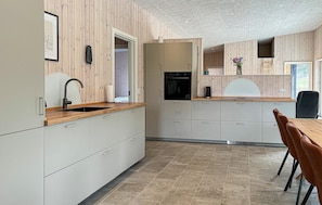 Eine moderne Küche mit Holzausstattung, einem eingebauten Ofen und einem Essbereich mit Tisch und Stühlen.