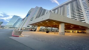 Entrada de hotel con zona exterior cubierta, varios pisos y un diseño arquitectónico moderno.