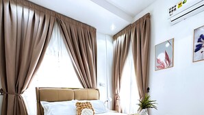 Ein modernes Schlafzimmer mit einem großen Bett, hellbeigen Vorhängen, einem Nachttisch und einer wandmontierten Klimaanlage.