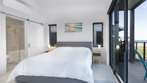 A modern bedroom with a large bed, a glass shower enclosure, and a balcony with a view.