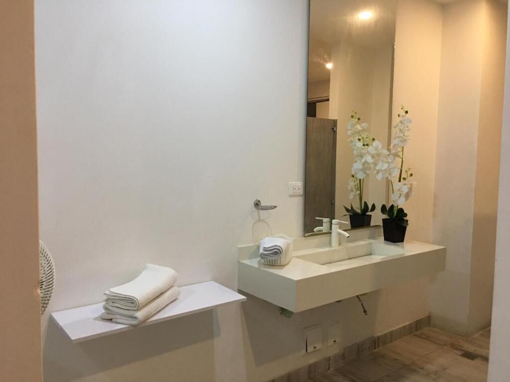 Une salle de bain moderne avec un lavabo blanc, un grand miroir et un porte-serviettes.