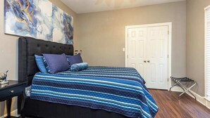 Ein Schlafzimmer mit einem großen Bett, einem dunklen Kopfteil, einer weißen Tür und einem kleinen Nachttisch.
