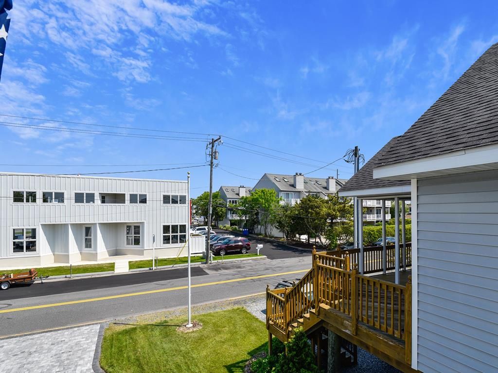 A residential street with a modern building, a wooden deck, and a clear sky.