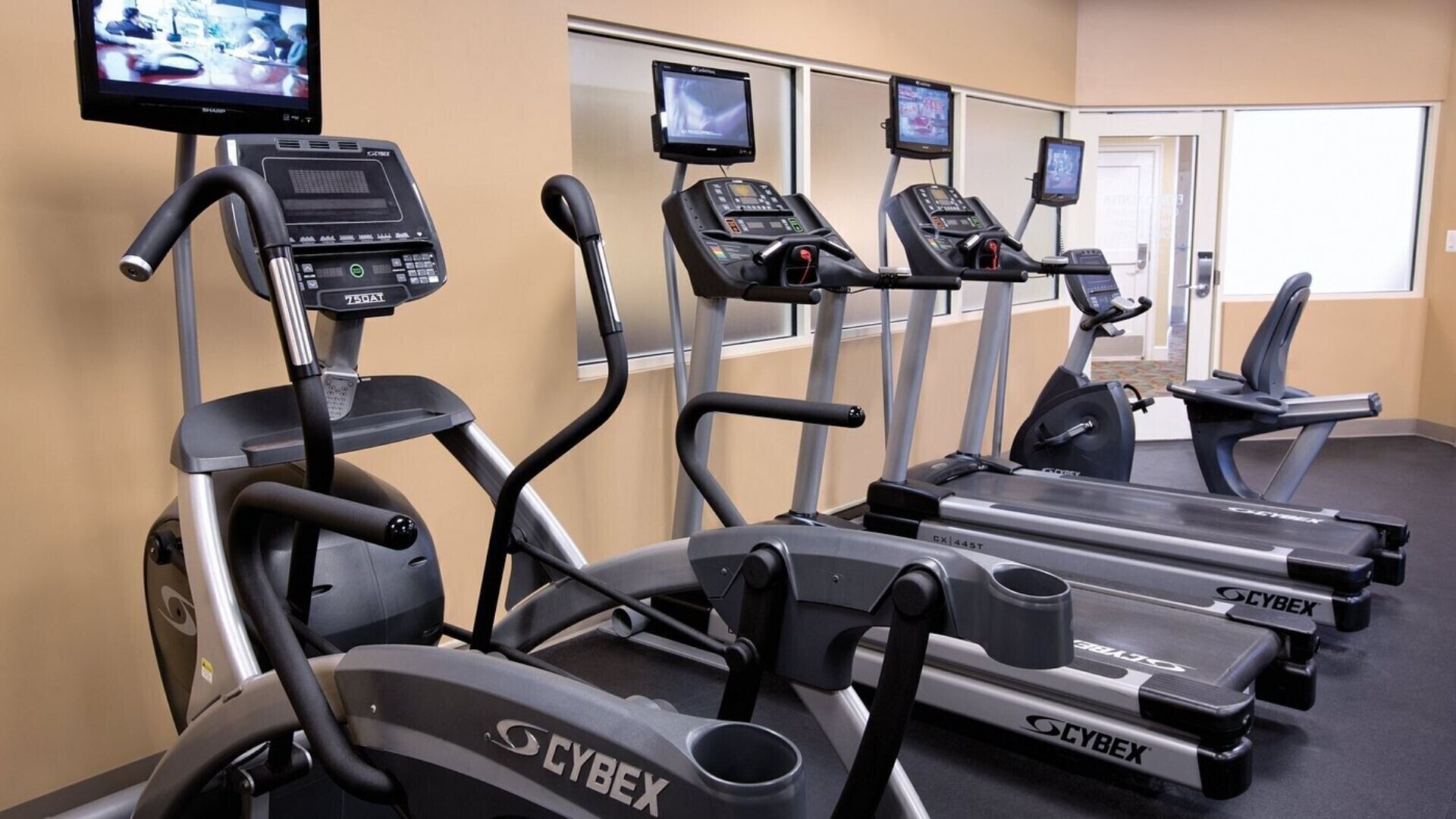 A gym with multiple treadmills, each equipped with digital displays and control panels.