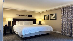 A hotel room with a large bed, two bedside lamps, a clock, framed artwork on the wall, and a curtain with a leaf pattern. - Asian inspired decor in this beautiful studio (Honolulu)