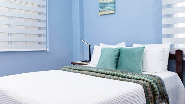 Une chambre à coucher avec un lit, une table de chevet, une lampe et un tableau au mur.
