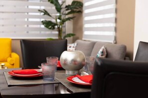 A dining table set with red plates, clear glasses, and a silver bowl. - Ahra Suites come for the views (Ground Floor) (Arnos Vale)