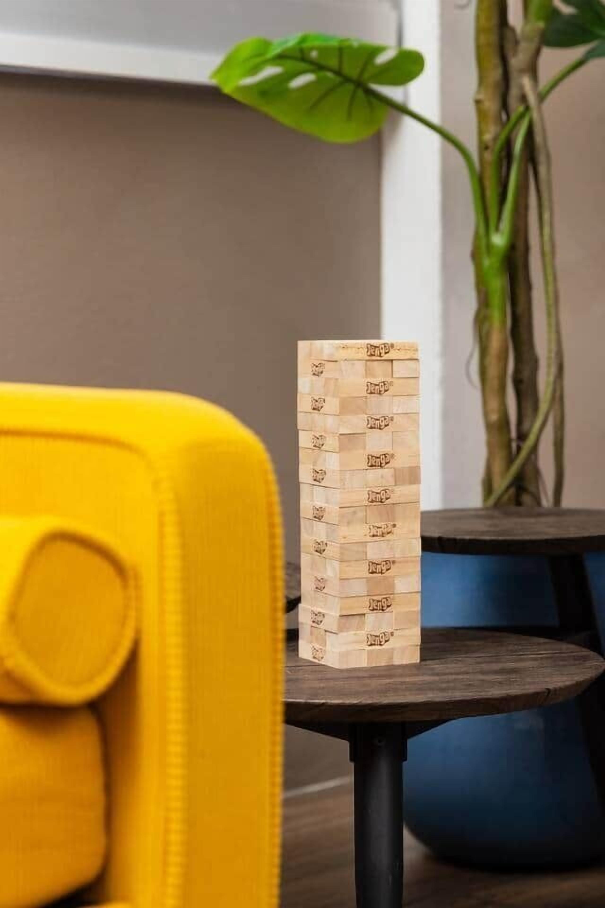 Una torre de bloques de madera sobre una mesita con una silla amarilla al frente.