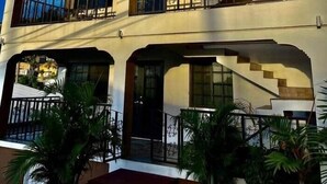 Un immeuble à plusieurs étages doté de balcons, d’escaliers et de plantes en pot.