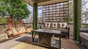 A covered patio area with a sofa, chairs, and a coffee table. - Historic Home with King Bed (High Point)