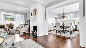 A spacious living room with a fireplace, a dining area with a chandelier, and a view of the outdoors. - Historic Home with King Bed (High Point)