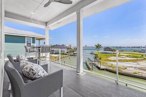 A balcony with outdoor furniture, a view of the water, and a distant shoreline. - Sea Breeze Bliss Vacation Home (Fort Myers Beach)