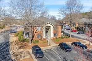 A residential building with a garage, parked cars, and a driveway.