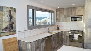 A modern kitchen with a large window, stainless steel appliances, and a view of buildings.