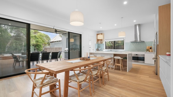 A modern kitchen with a large island, wooden chairs, and a dining table.