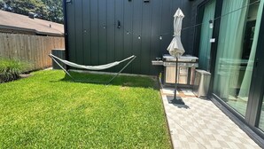 Un patio trasero con una hamaca, una parrilla y un área de patio.