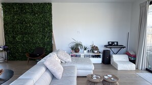 Una sala de estar moderna con una pared verde, un sofá, una mesita de centro, un teclado y un altavoz.