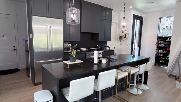Una cocina moderna con armarios oscuros, electrodomésticos de acero inoxidable y una isla central con taburetes de bar.