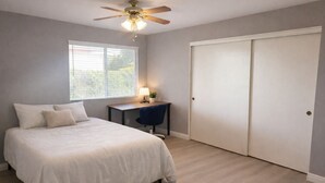 A bedroom with a bed, a desk, a chair, a ceiling fan, and a wardrobe. - Spacious 4BR Norco Retreat; Near SilverLakes; Pet Friendly; RV Parking (Norco)