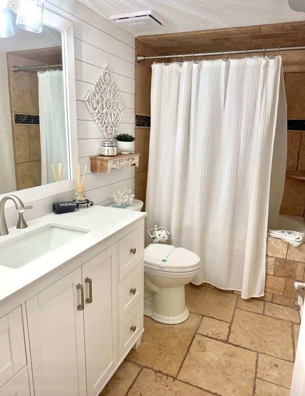 A bathroom with a white sink, vanity, and toilet, a shower curtain, and a decorative mirror. - Seascape Villa: Beach Access, Pools, Golf, Music (Miramar Beach)
