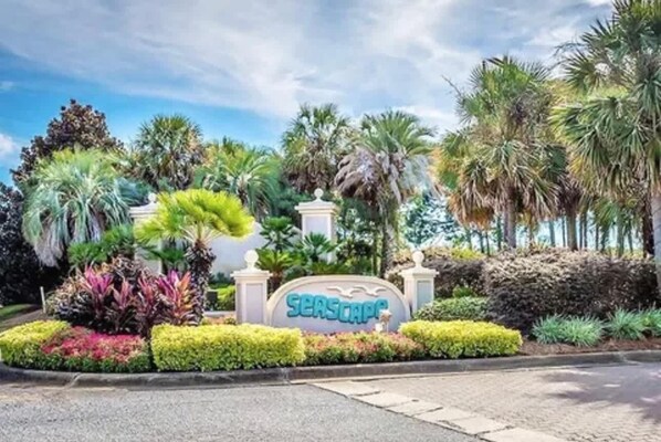 A sign with the name 'SEASCAPE' surrounded by lush greenery and palm trees. - Seascape Villa: Beach Access, Pools, Golf, Music (Miramar Beach)