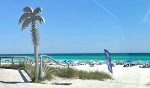 A beach with a palm tree sculpture, a flag, and a clear blue sky. - Seascape Villa: Beach Access, Pools, Golf, Music (Miramar Beach)