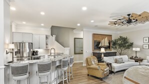 Una cocina moderna con barra, una mesa de comedor y una sala de estar con sofá y sillón.