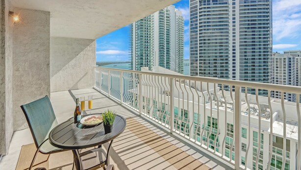 Un balcon avec une table, des chaises et une bouteille d’eau.