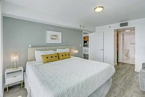 Ein Schlafzimmer mit einem großen Bett, einem Nachttisch, einer Wanddekoration und einer Tür zu einem Badezimmer.