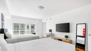 A modern hotel room with two beds, a TV, a desk, and a large window. - Brickell Condo w Pool, Gym, Balcony & Parking (Miami)