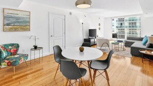A modern living room with a round dining table, black chairs, a sofa, and a television. - Brickell Condo w Pool, Gym, Balcony & Parking (Miami)