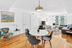 Ein modernes Wohnzimmer mit einem runden Esstisch, schwarzen Stühlen, einer Couch und einem Fernseher.
