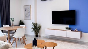 A modern living room with a sofa, a dining table with chairs, a TV, and a blue accent wall. - "Blue" – Adults Only (+16) (Sarandë)
