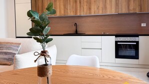 A modern kitchen with wooden cabinets, a built-in oven, and a dining table with a glass vase. - "Blue" – Adults Only (+16) (Sarandë)
