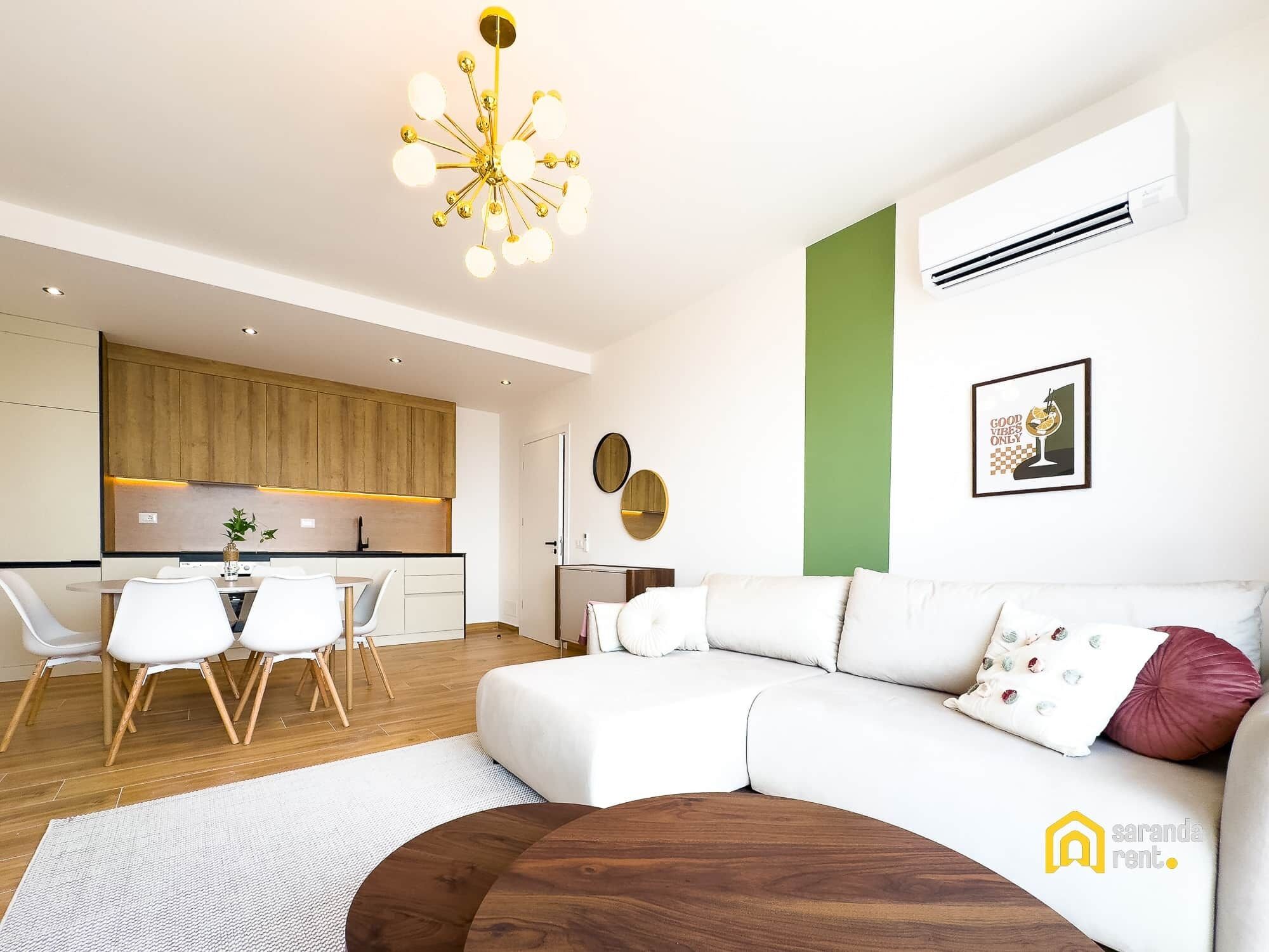 A modern living room with a white sofa, a wooden coffee table, and a dining area with a white table and chairs.
