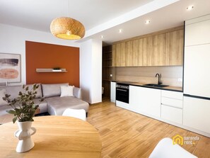 A modern kitchen with wooden cabinets, a black sink, and a built-in oven.
