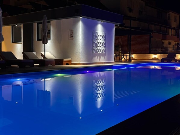 En swimmingpool med en geometrisk lampe og liggestole.