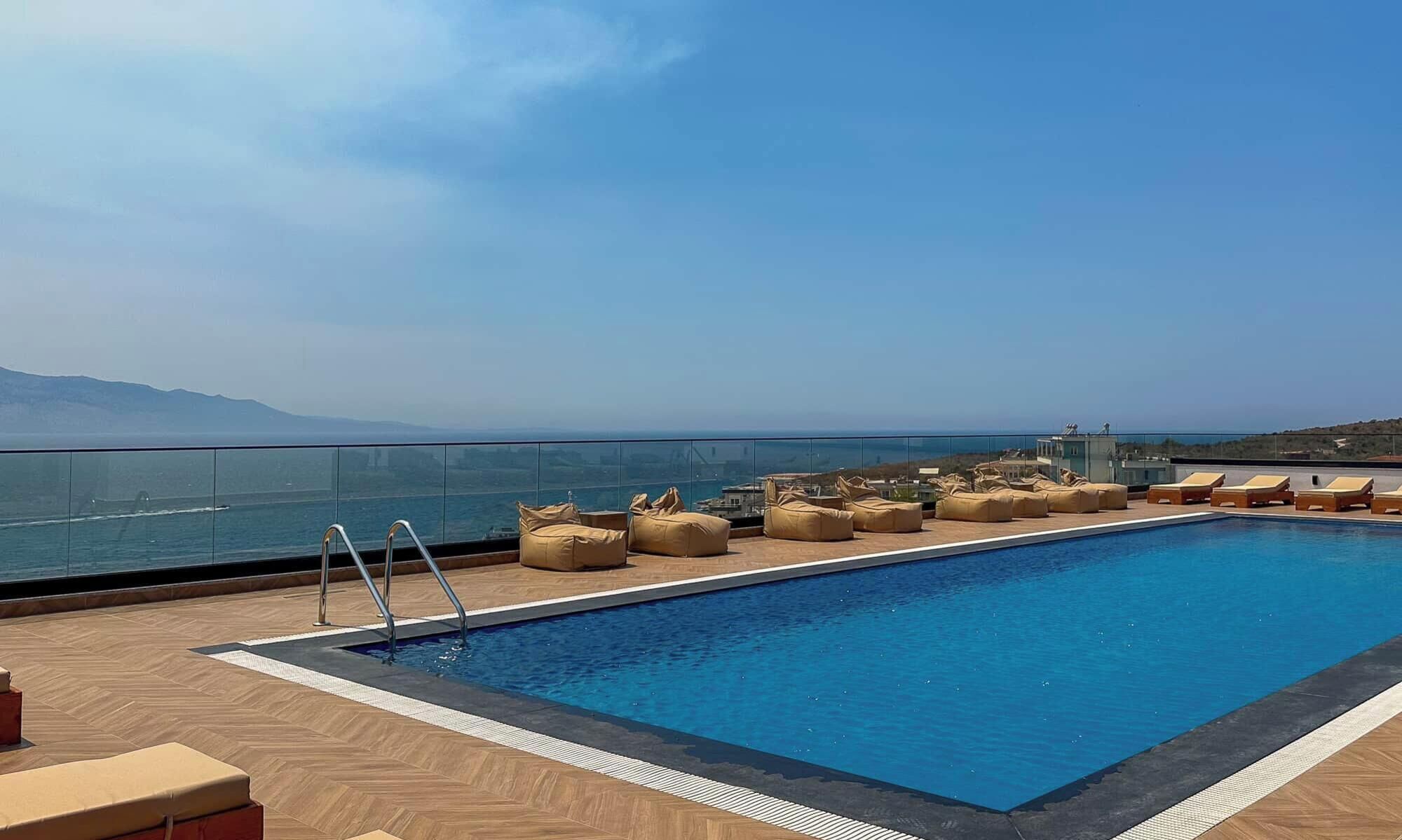 A rooftop pool with lounge chairs and a view of the sea.