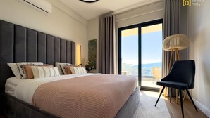 Een moderne slaapkamer met een groot bed, uitzicht op de stad en een stoel bij het raam.