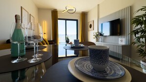 Een moderne hotelkamer met een zithoek, een bank, een aan de muur bevestigde televisie en uitzicht over de stad.