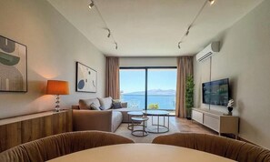 A modern hotel room with a sofa, two small tables, a TV, and a large window with a view of the sea. - "Mamma Mia" – Adults Only (+16) (Sarandë)