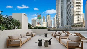 Eine Dachterrasse mit Sitzgelegenheiten im Freien und Blick auf die Stadt.