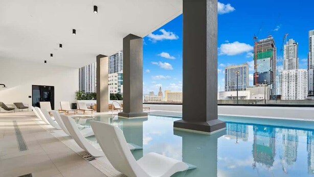 Ein moderner, überdachter Pool mit freiem Blick auf die Stadtlandschaft, darunter Hochhäuser und Baukräne.